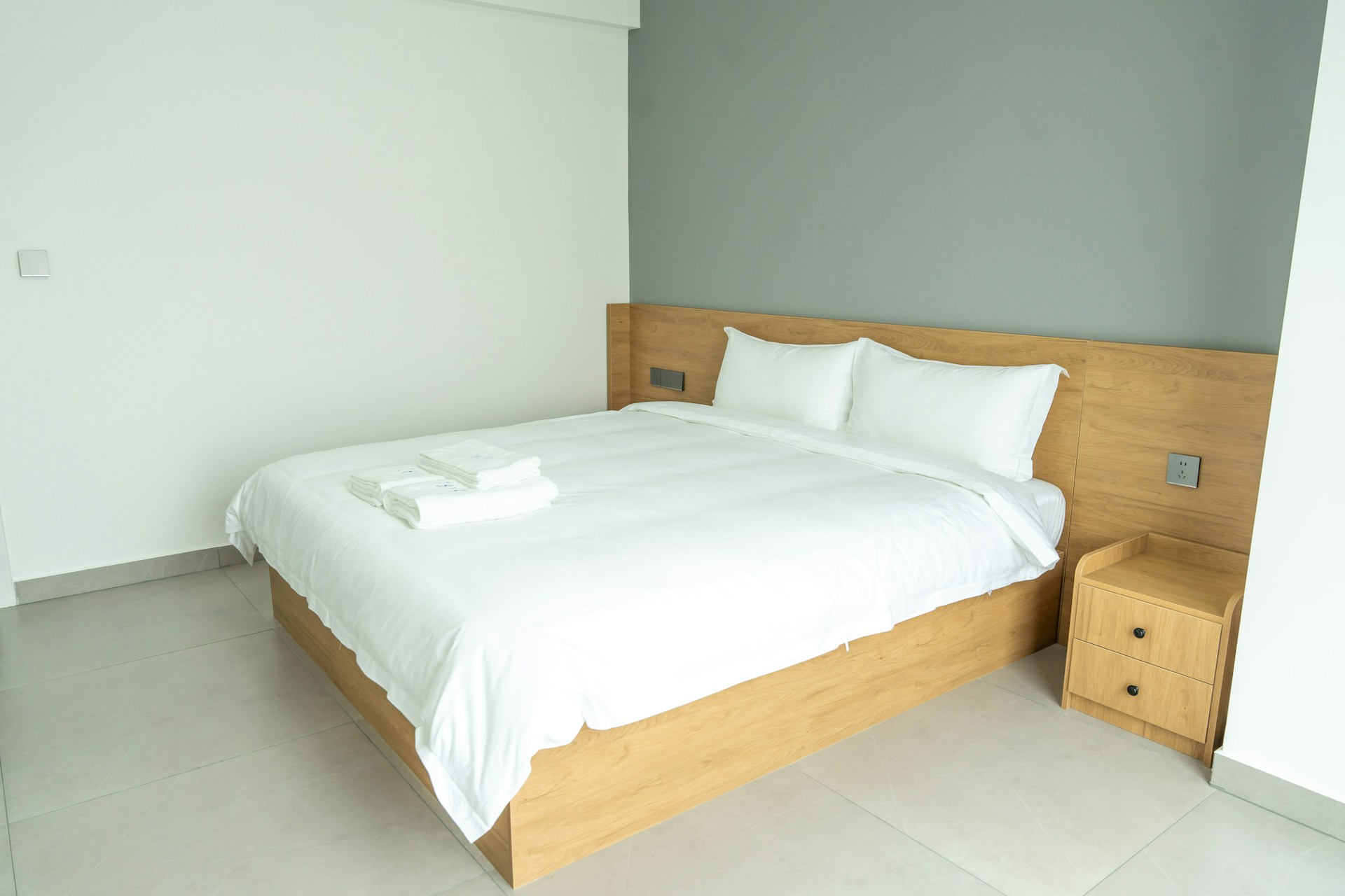 Sauber bezogenes Doppelbett in einem hellen, modernen Schlafzimmer