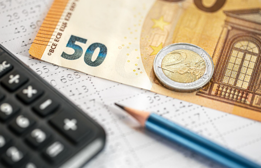 Ein 50-Euro-Schein, eine 2-Euro-Münze, ein Taschenrechner und ein Bleistift auf einem Finanzdokument.