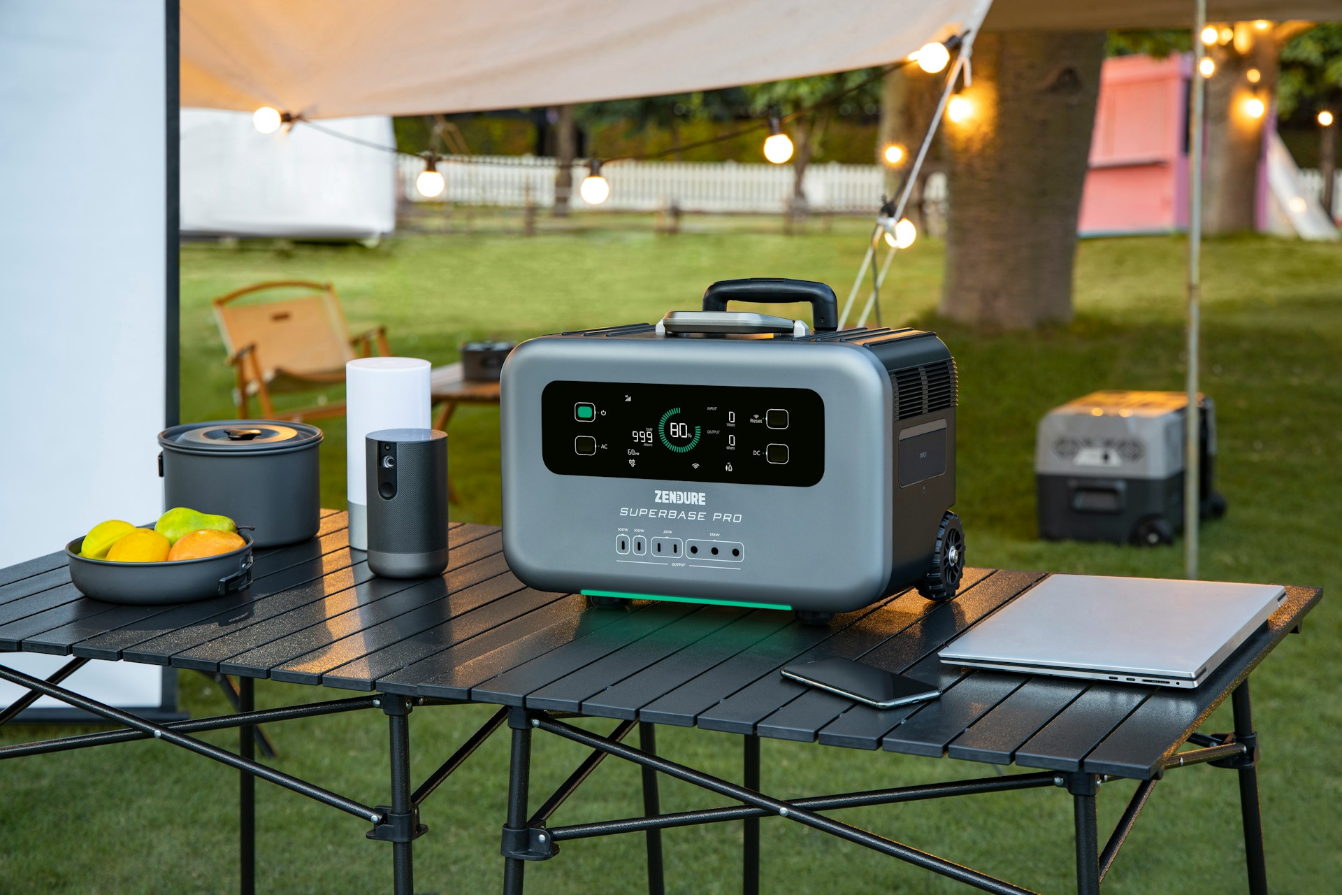 Powerstation auf einem Campingtisch zur Stromversorgung von Laptop und weiteren Geräten.